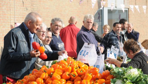 Mensen op de weekmarkt bij groente- en fruitkraam